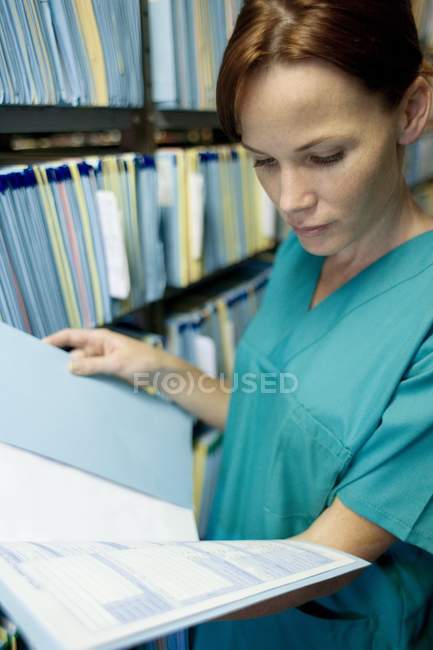 Enfermeira leitura de prontuário na sala de armazenamento . — Fotografia de Stock