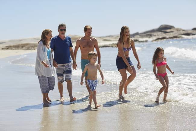 Famille de trois générations marchant ensemble sur la plage . — Photo de stock