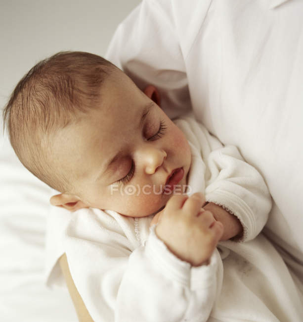 Menina bebê dormindo nos braços da mãe . — Fotografia de Stock
