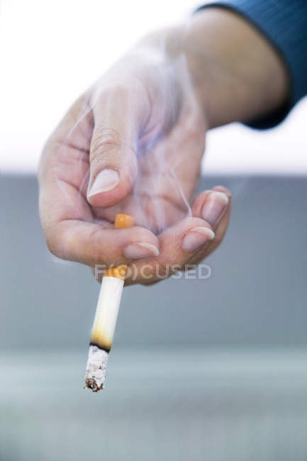 Дим піднімається від запалену сигарету в жіночих рук. — стокове фото