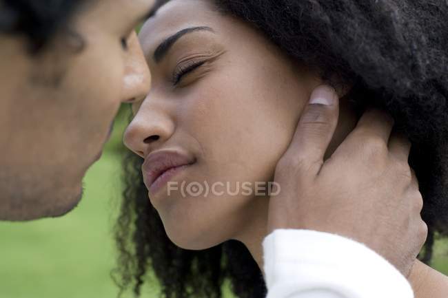 Young couple leaning to kiss outdoors. — Stock Photo