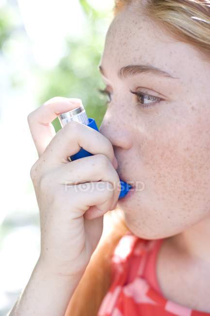 Portrait of teenage redhead girl using inhaler for treating asthma attack. — Stock Photo