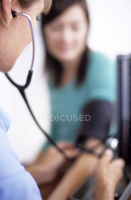 Doctor using sphygmomanometer and stethoscope for measuring patient blood pressure. — Stock Photo