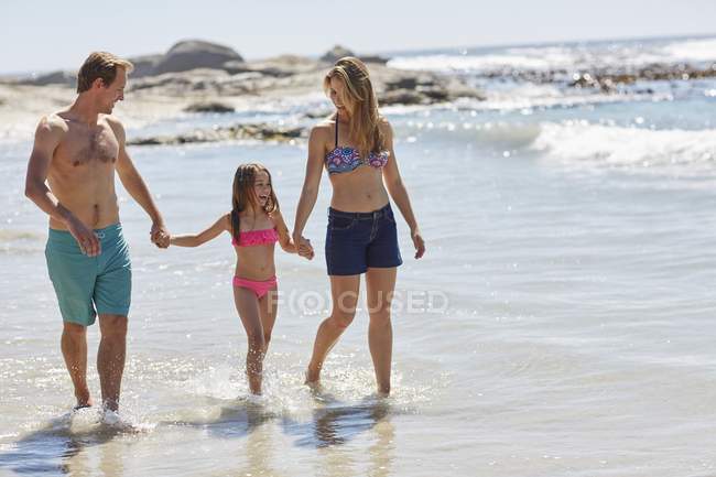 Mère et père marchant sur la plage avec leur fille . — Photo de stock