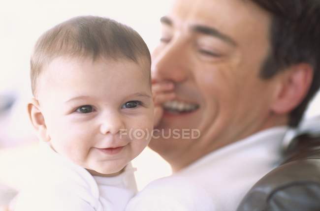 Padre sosteniendo bebé bebé niña y riendo . - foto de stock