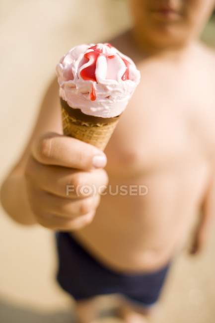 Close-up of boy holding ice cream cone on beach. — Stock Photo