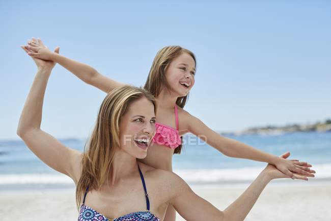 Madre e figlia sulla spiaggia con le braccia tese . — Foto stock