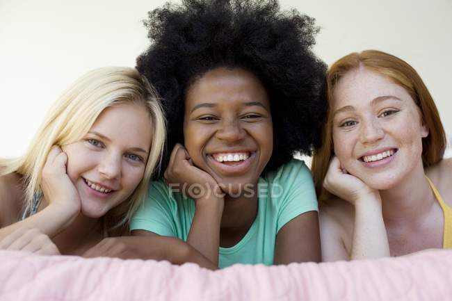 Три веселий дівчат-підлітків гуляти на ліжку в приміщенні. — стокове фото