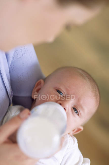 Mãe alimentando bebê menino com garrafa de leite . — Fotografia de Stock