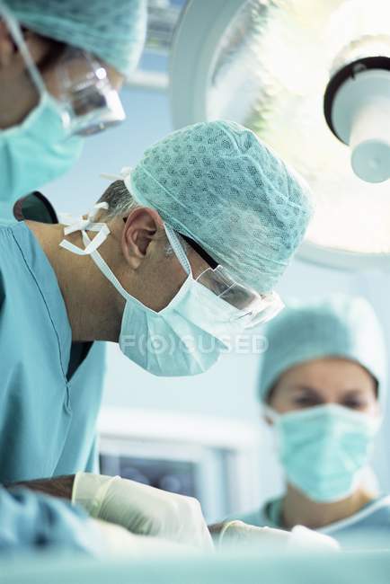 Team of surgeons performing operation in operating theater. — Stock Photo