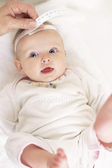 Female hand using tape for measuring circumference of baby girl head. — Stock Photo