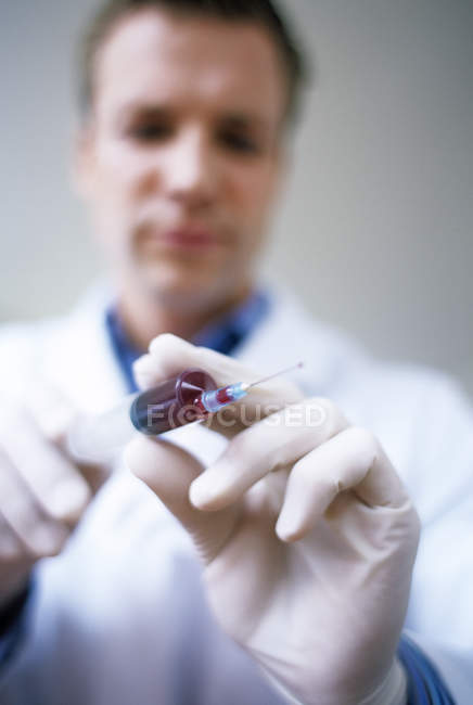 Close-up of syringe full of blood in hands of male doctor. — Stock Photo