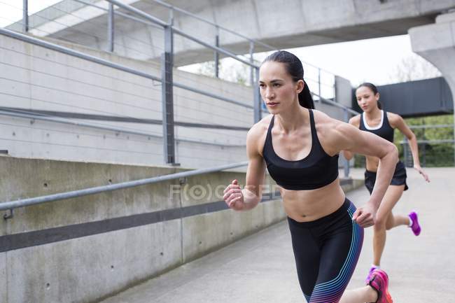 Mujeres jóvenes corriendo en la escena urbana . - foto de stock