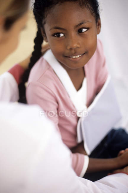 Female doctor talking girl with injured arm in sling. — Stock Photo
