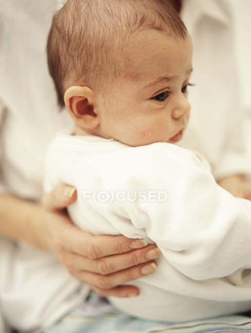 Mother supporting baby girl while sitting on lap. — Stock Photo