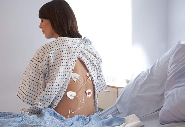 Paciente do sexo feminino sentada em enfermaria com estimulação elétrica nervosa transcutânea . — Fotografia de Stock