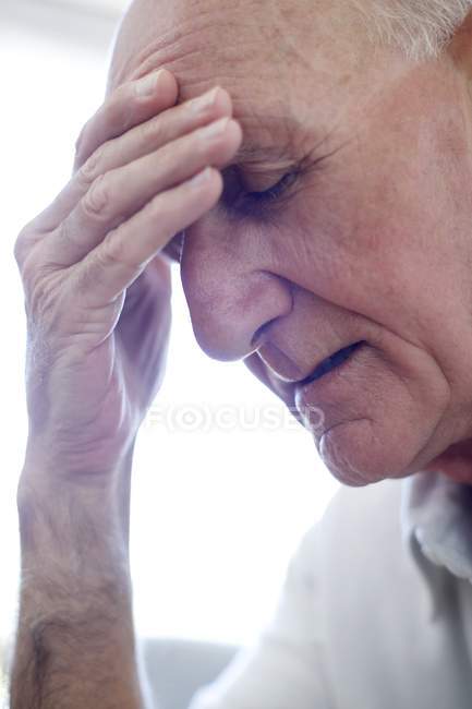 Portrait of senior man with hand on forehead. — Stock Photo
