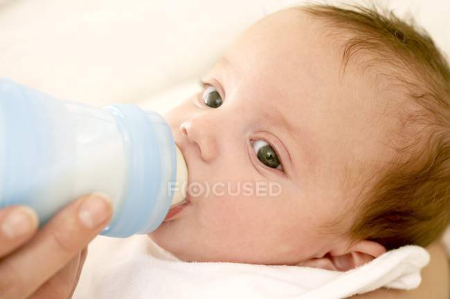 Mutter füttert Baby-Tochter mit Milch aus Flasche. — Stockfoto