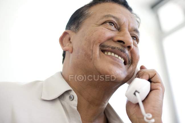 Портрет улыбающегося взрослого мужчины, разговаривающего по кабельному телефону . — стоковое фото