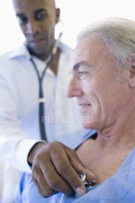 Doctor using stethoscope and listening to patient chest. — Stock Photo