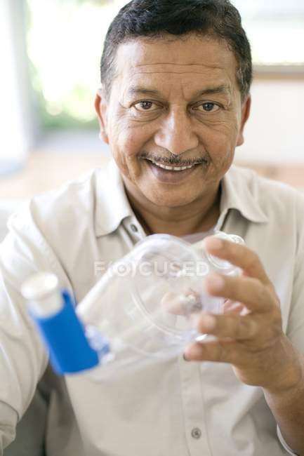 Homem maduro usando espaçador de asma com inalador de asma azul . — Fotografia de Stock
