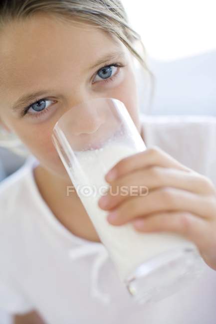 Девочка младшего возраста пьет молоко из стекла . — стоковое фото