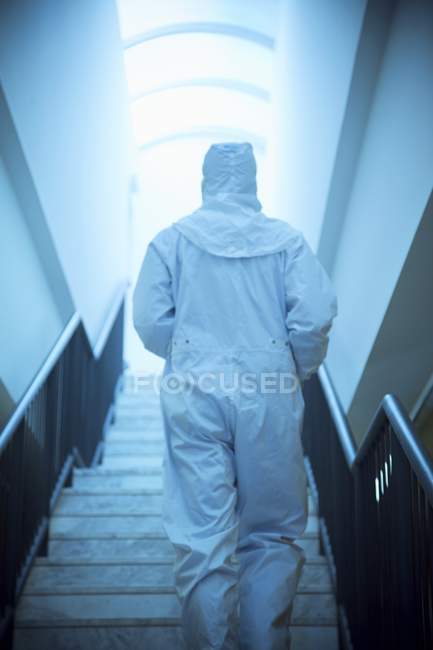 Rückansicht eines männlichen Wissenschaftlers im weißen Isolationsanzug beim Treppensteigen. — Stockfoto