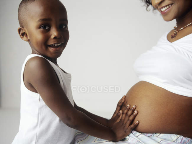 Preschooler boy touching swollen abdomen of pregnant mother. — Stock Photo