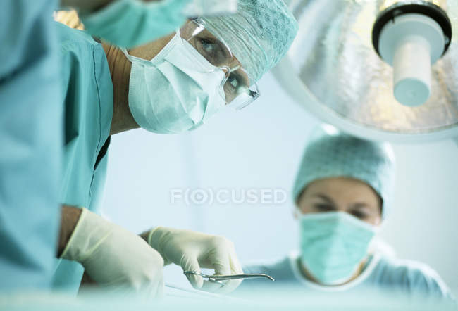 Chirurgo che parla con i colleghi durante l'operazione in sala operatoria . — Foto stock