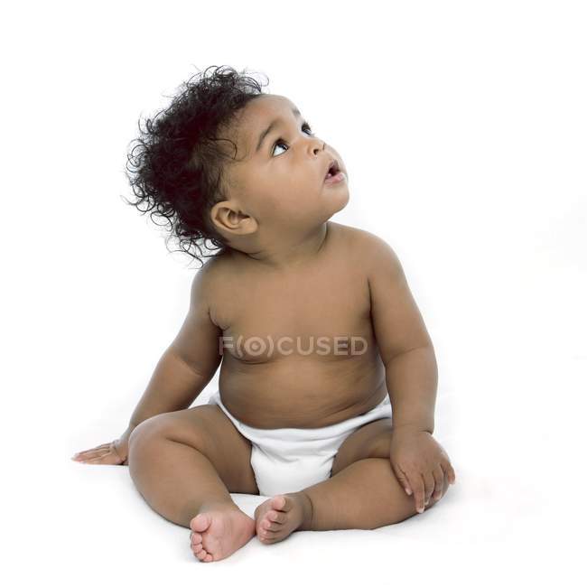 Bébé fille assis et regardant vers le haut sur fond blanc . — Photo de stock