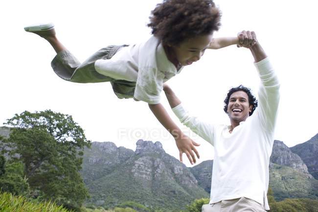 Father playfully throwing son in park. — Stock Photo