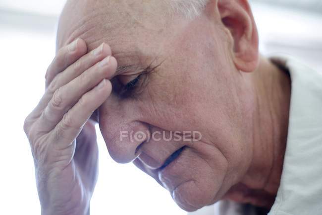 Portrait of senior man with hand on forehead. — Stock Photo