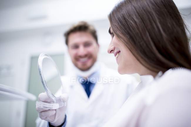 Patientin in Zahnklinik überprüft Zähne im Spiegel. — Stockfoto