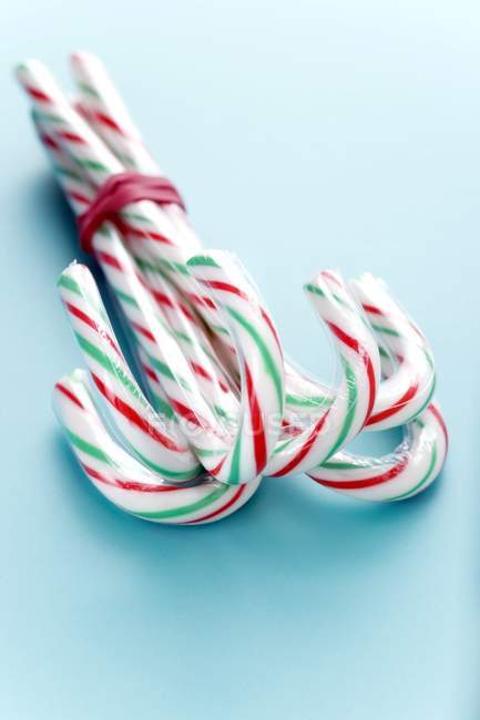 Candy canes tied together on blue background — Stock Photo