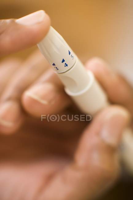 Close-up da mão feminina usando dispositivo de lancing semelhante a caneta para teste de picada . — Fotografia de Stock