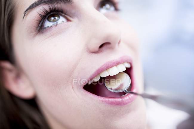 Primer plano de la mujer que se somete a examen dental con espejo bucal . - foto de stock