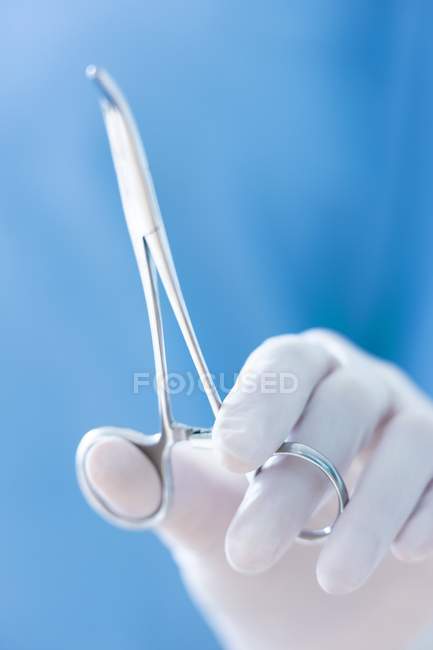 Vista de cerca de las pinzas quirúrgicas en la mano del médico . - foto de stock