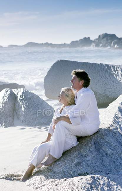 Mature couple sitting on rock and looking at view. — Stock Photo