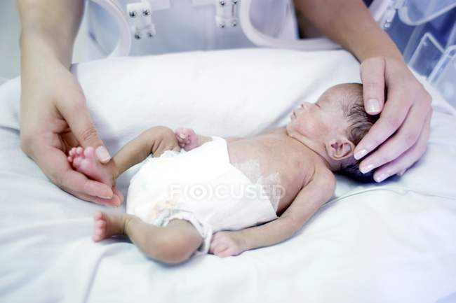 Primo piano dell'infermiera che tiene in braccio un bambino prematuro . — Foto stock