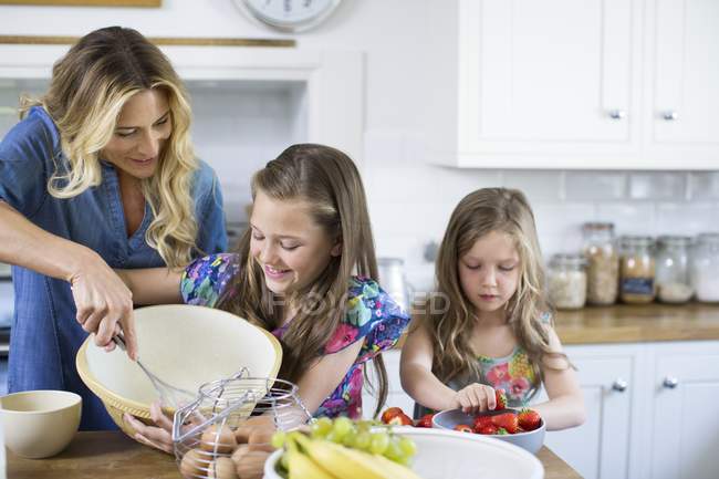 Mother and daughters cooking together in kitchen. — Stock Photo