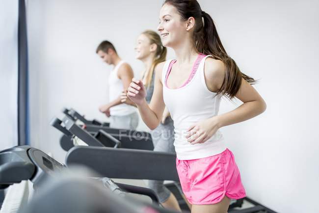 Жінки і чоловік вправляються на бігових доріжках у спортзалі . — стокове фото
