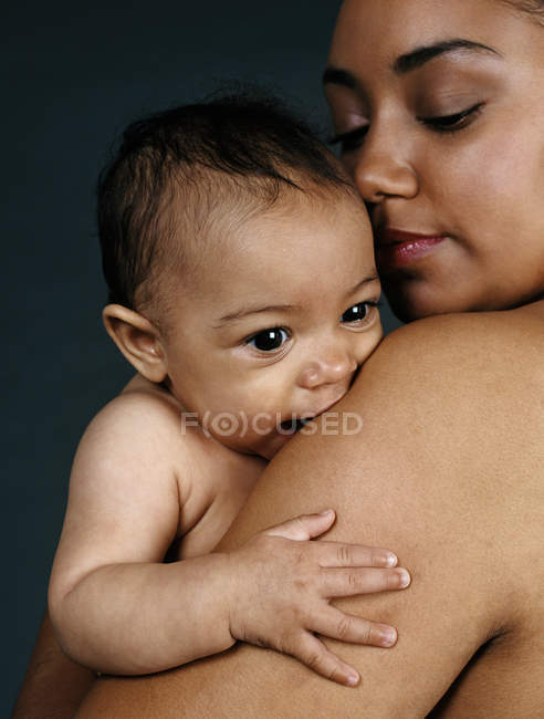 Madre sosteniendo bebé niña y mirando hacia abajo . - foto de stock
