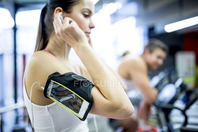Young woman listening to music while working out in gym. — Stock Photo