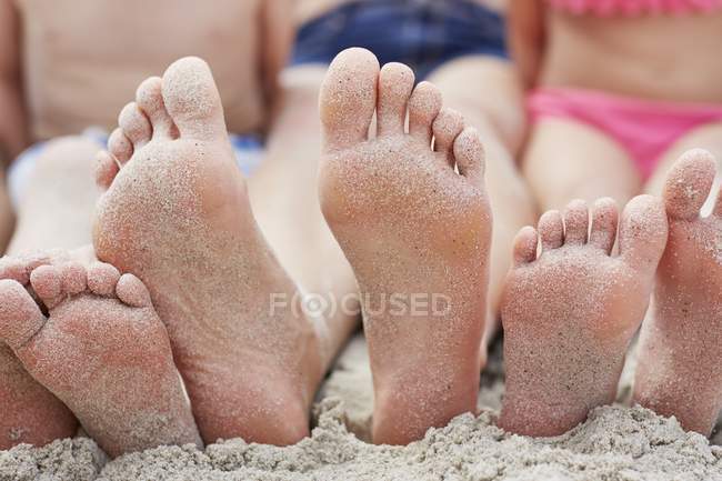 Famiglia seduta sulla spiaggia con i piedi scalzi . — Foto stock