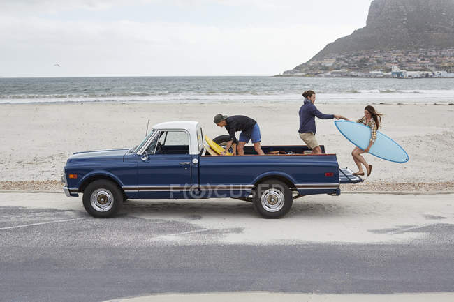 Frau steigt mit Männern auf Pick-up-Truck am Strand. — Stockfoto