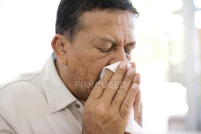 Hombre maduro estornudando en el pañuelo
. - foto de stock
