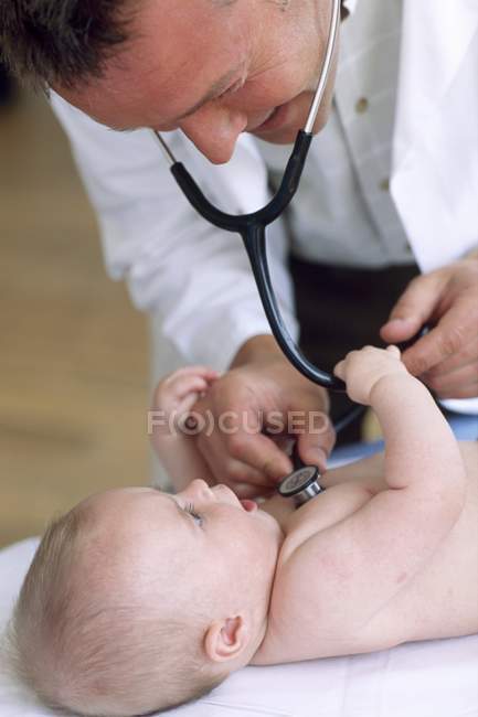 Médico usando estetoscópio para ouvir batimentos cardíacos de bebê recém-nascido . — Fotografia de Stock