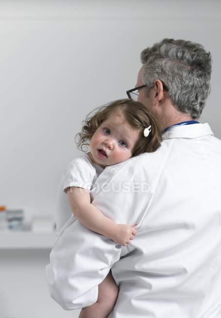 Male pediatrician holding toddler girl. — Stock Photo