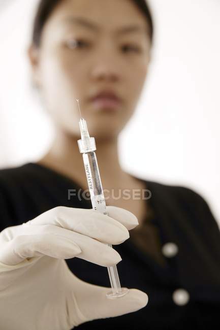 Clinician holding hypodermic syringe in gloved hand. — Stock Photo