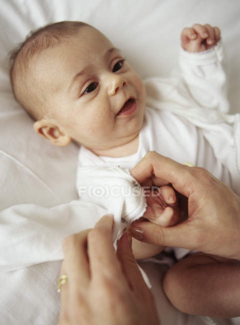 Mãe mãos mudando de roupa de bebê menina . — Fotografia de Stock